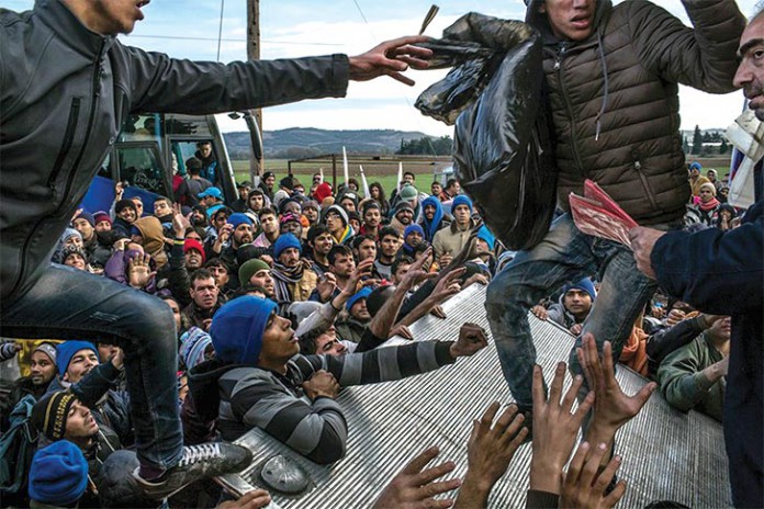 Imagem do brasileiro Maurício Lima mostra refugiados, de países como Paquistão e Argelia, na Grécia, à espera de distribuição de água e cobertores
