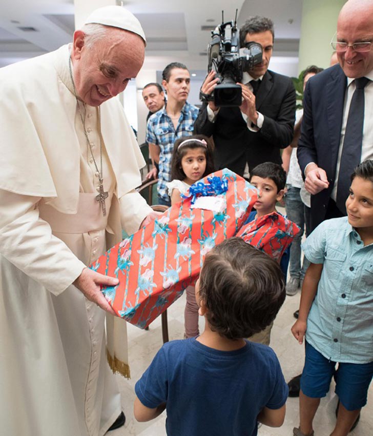 Papa entrega brinquedo para criança refugiada