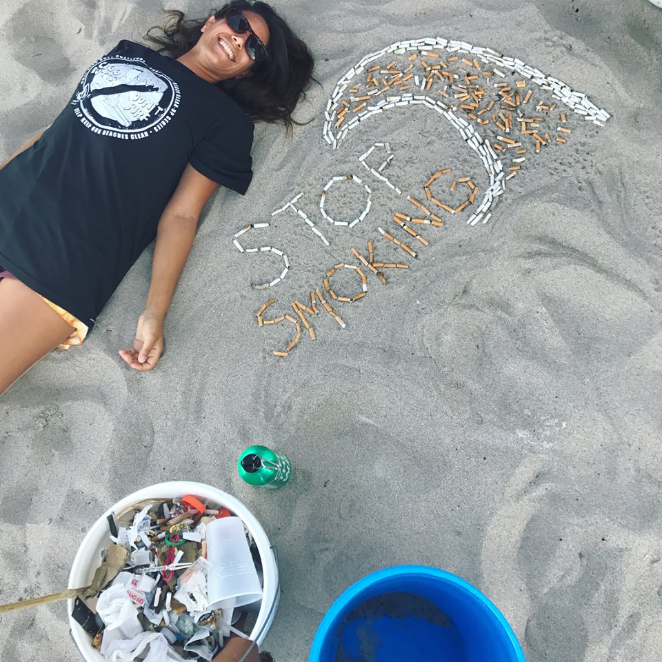 Voluntária posa ao lado das pontas de cigarro encontradas na praia de Deerfield Beach