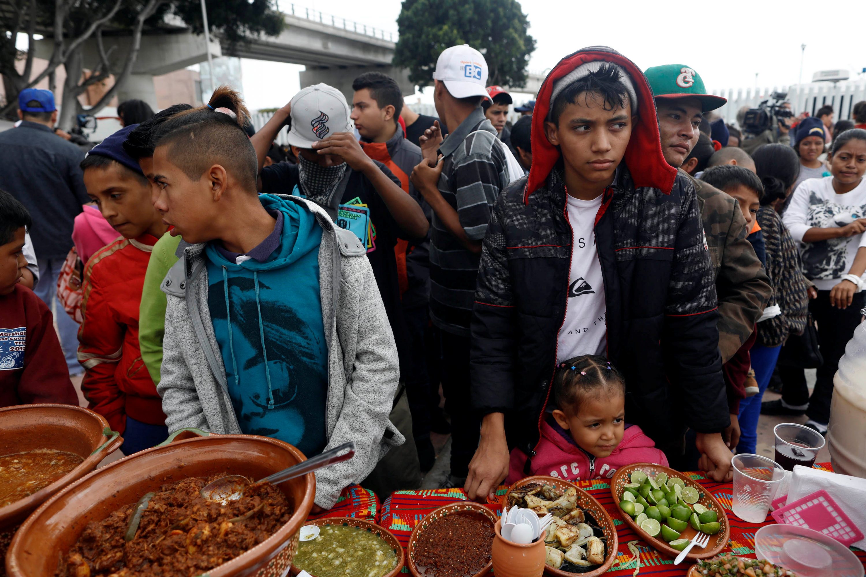 Membros da caravana de imigrantes que cruzaram a fronteira dos EUA com México recebem comida (Foto: Reuters)