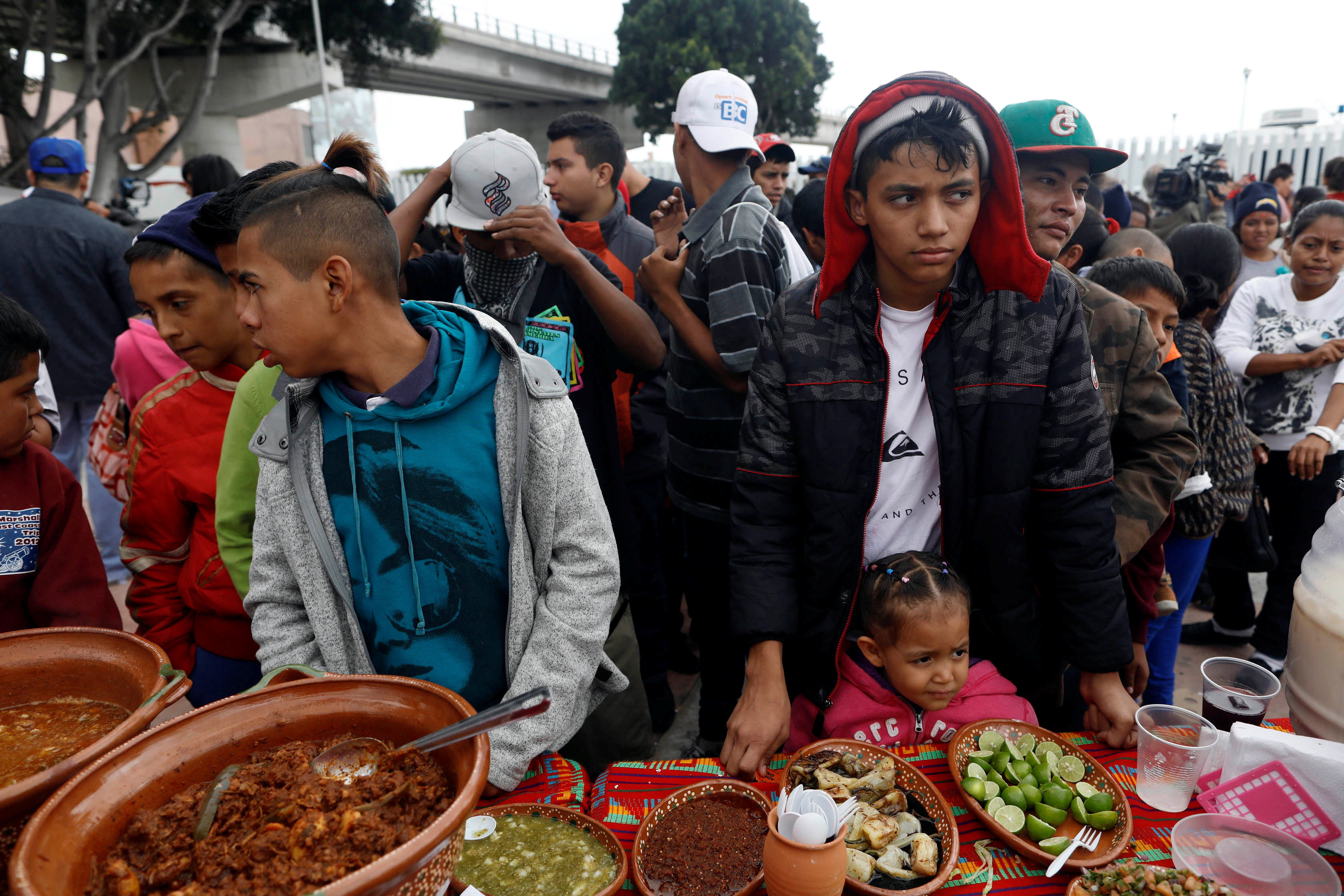 Membros da caravana de imigrantes que cruzaram a fronteira dos EUA com México recebem comida (Foto: Reuters)