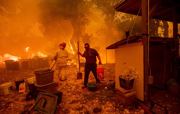 Moradores tentam salvar casa em New Long Valley, na Califórnia, no sábado (4) Foto Noah Berger AFP