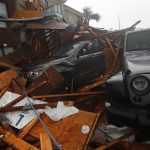 A storm chaser climbs into his vehicle during the eye of Hurricane Michael to retrieve equipment after a hotel canopy collapsed in Panama City Beach, Fla., Wednesday, Oct. 10, 2018. (AP Photo/Gerald Herbert)