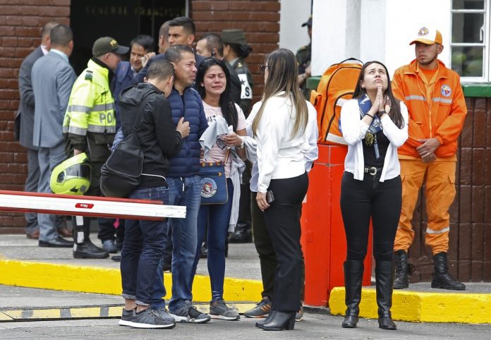Familiares de vítimas se reúnem na entrada da Academia General Santander, em Bogotá, onde um carro-bomba explodiu — Foto AP Photo John Wilson Vizcaino