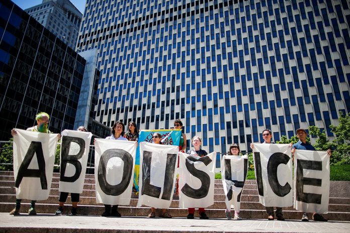 People pose for a picture in front of ICE's offices at the federal building during a protest against family deportations in the Manhattan borough of New York