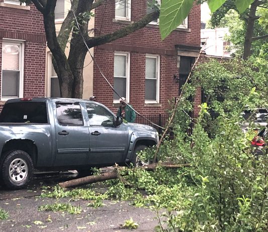 Moradores observam cabo de eletricidade caído em rua no Queens após a passagem da tempestade tropical Isaías