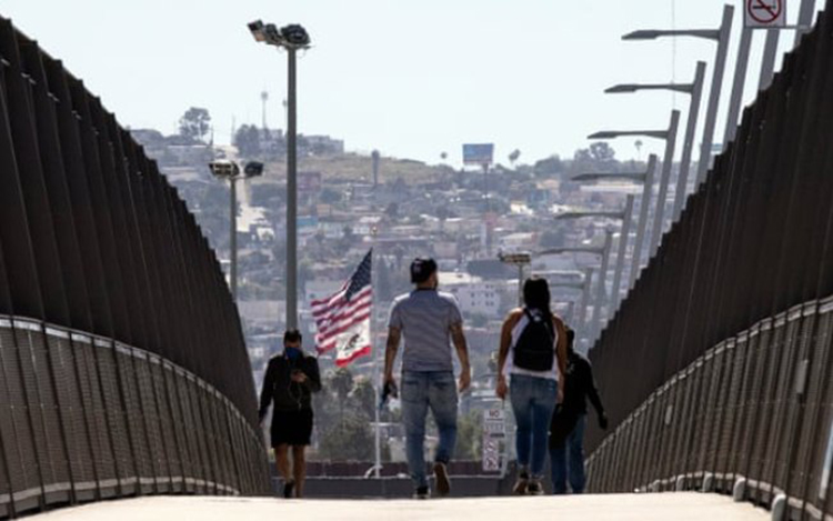 Pessoas usando máscaras cruzam a ponte sobre a rodovia na fronteira EUA-México em San Diego, Califórnia (Foto: Étienne Laurent/divulgação)