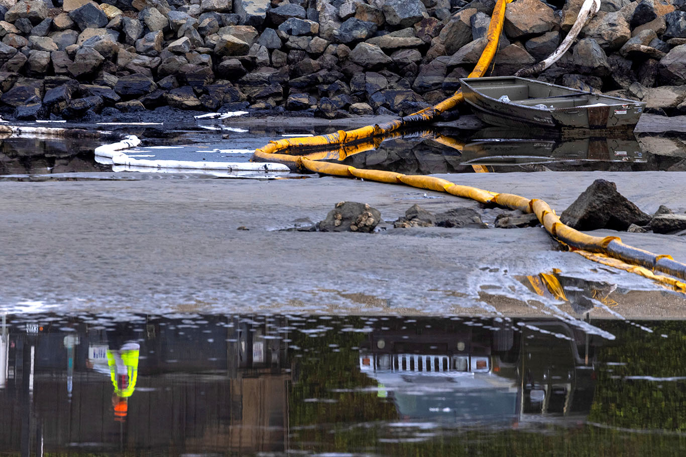 Um trabalhador é refletido na água de um estuário após um grande derramamento de óleo na costa da Califórnia chegar à costa em Huntington Beach, Califórnia (Foto: REUTERS/Mike Blake)