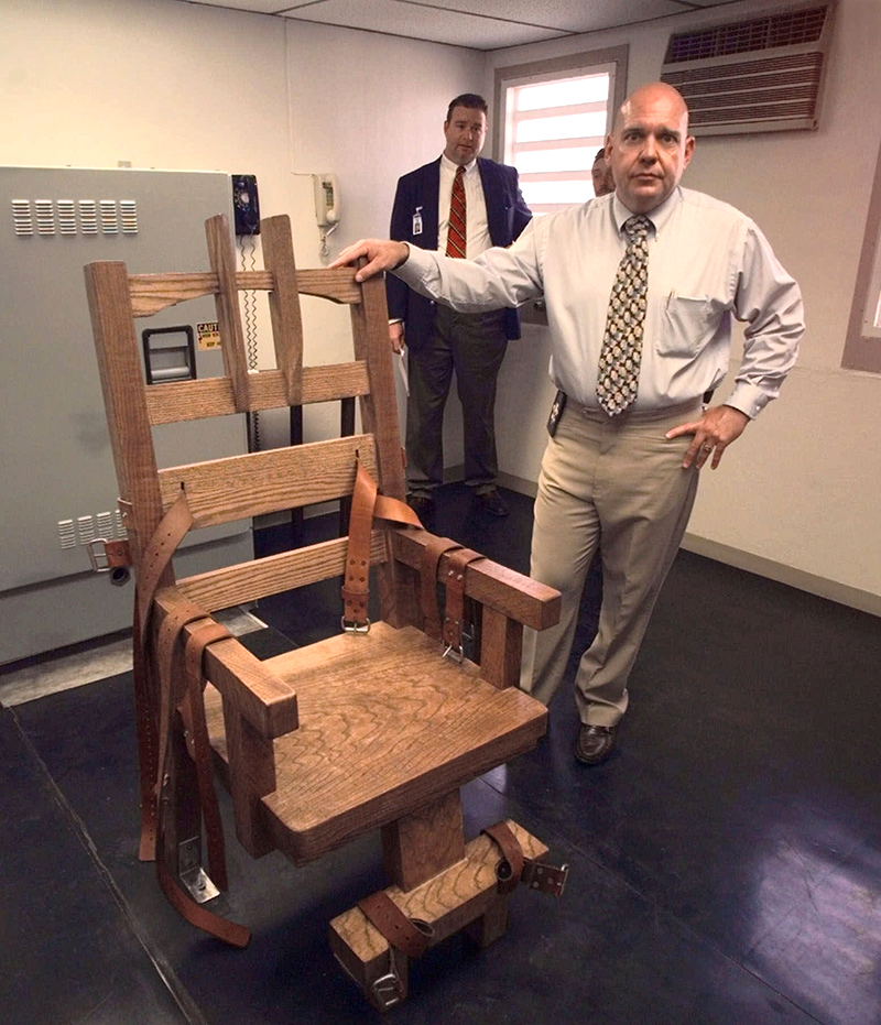 Diretor da prisão estadual da Flórida, James Crosby, ao lado de uma cadeira elétrica construída em agosto de 1999 (Foto: Mark Foley/AP)