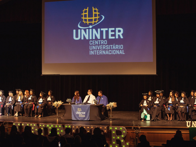 Formandos e mesa diretiva no palco da cerimônia de formatura